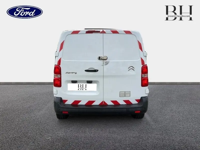 Vue arrière d'un Citroën Jumpy blanc Banquise avec marquages rouges réfléchissants et double portes arrière fermées.