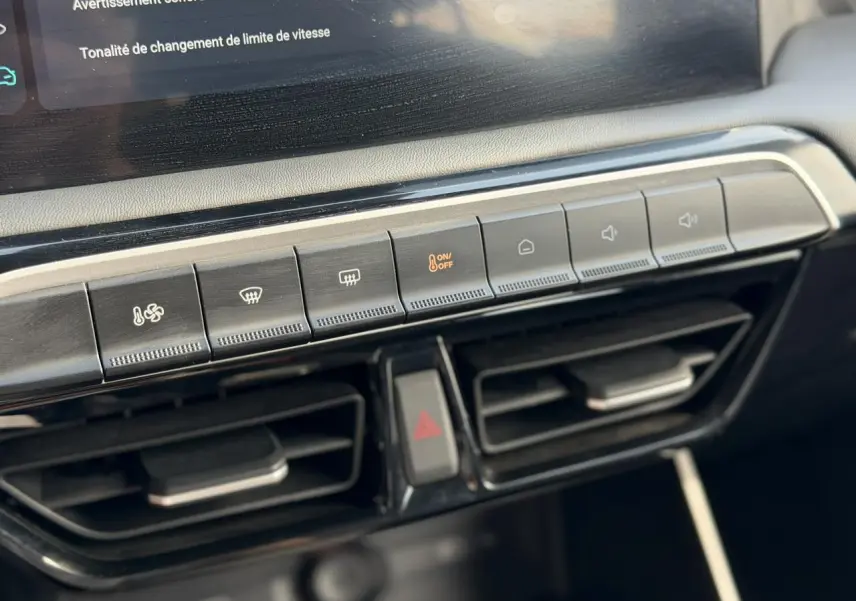 Gros plan sur la console centrale de la MG3 1.5 Hybrid+ 2025, montrant les boutons de climatisation et les aérateurs noirs.