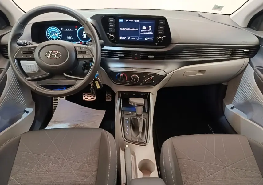 Vue intérieure avant de la Hyundai Bayon 2023, tableau de bord noir avec écran tactile central et volant cuir multifonctions.