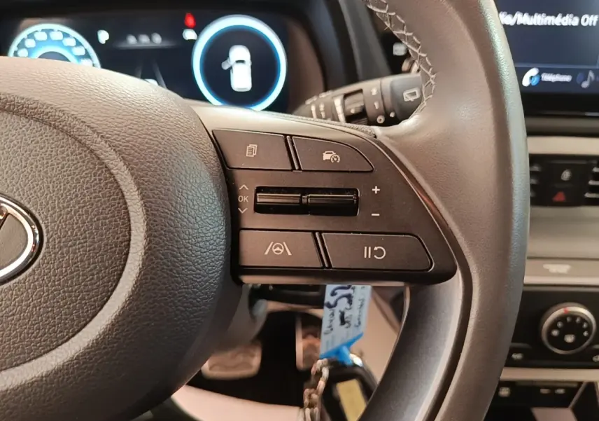 Gros plan sur le côté droit du volant cuir du Hyundai Bayon 2023 avec commandes multifonctions et tableau de bord numérique.