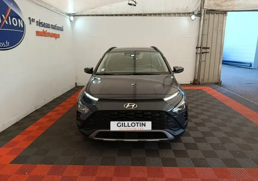 Vue avant d'un Hyundai Bayon gris foncé stationné en intérieur avec calandre noire et phares LED allumés.