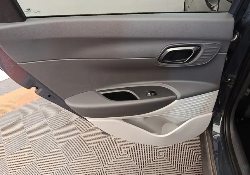 Vue intérieure de la porte arrière droite grise foncée de la Hyundai Bayon 2023 avec poignée et commande de fenêtre.