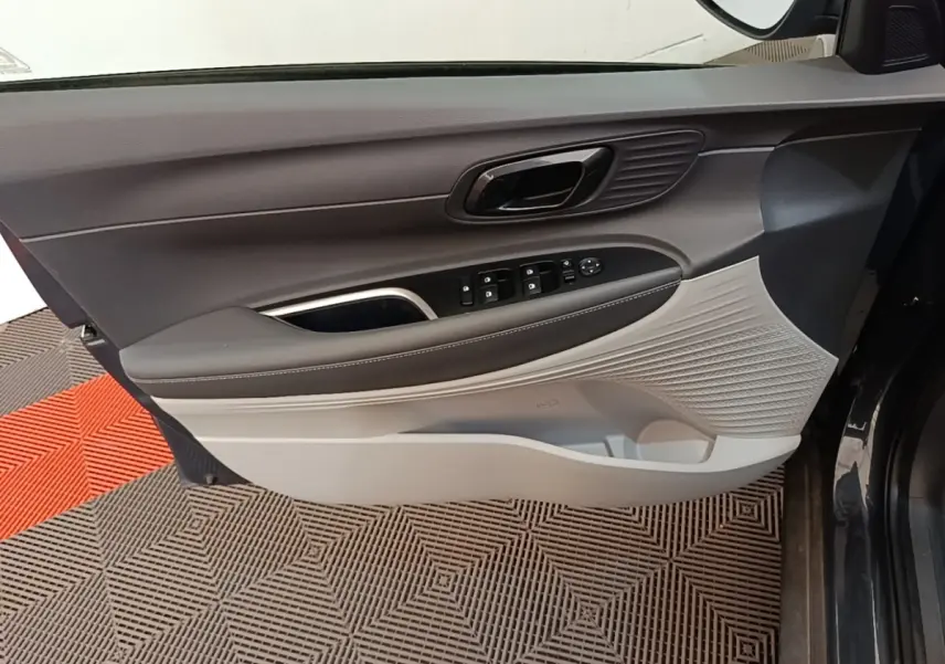 Vue intérieure côté gauche de la porte avant gris foncé de la Hyundai Bayon avec commandes de vitres et poignée intégrée.