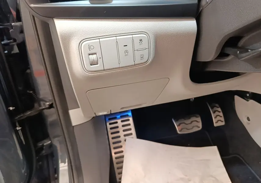 Détail intérieur côté conducteur du Hyundai Bayon gris foncé 2023, montrant les commandes d’éclairage et les pédales sport.
