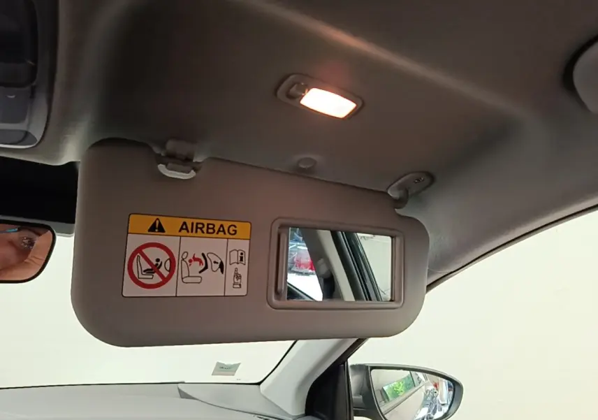 Vue intérieure côté conducteur du pare-soleil avec miroir et avertissement airbag dans un Hyundai Bayon gris foncé 2023.