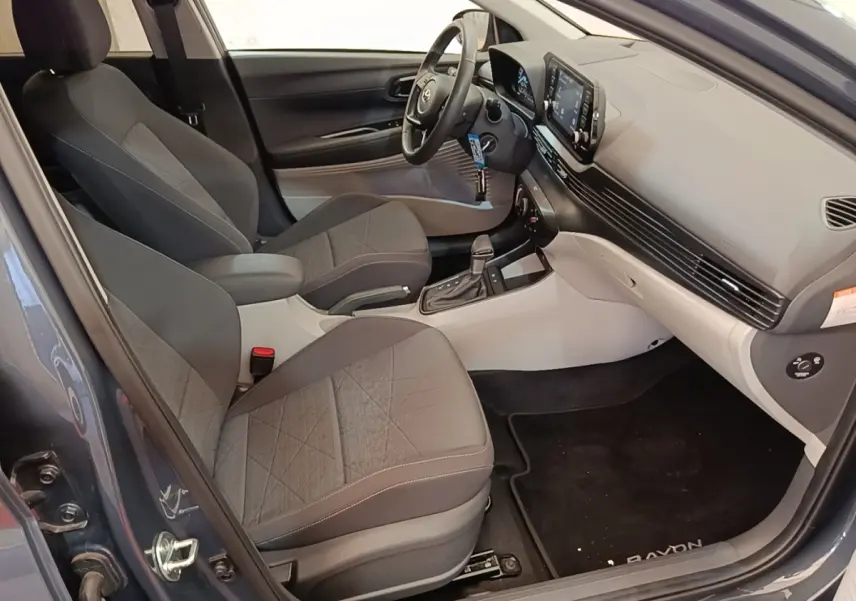 Vue intérieure côté conducteur de la Hyundai Bayon gris foncé 2023, avec sièges tissu et tableau de bord moderne.