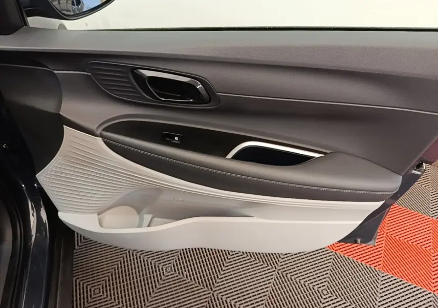 Vue rapprochée de la porte avant gauche de la Hyundai Bayon gris foncé, montrant le panneau intérieur bicolore noir et beige.
