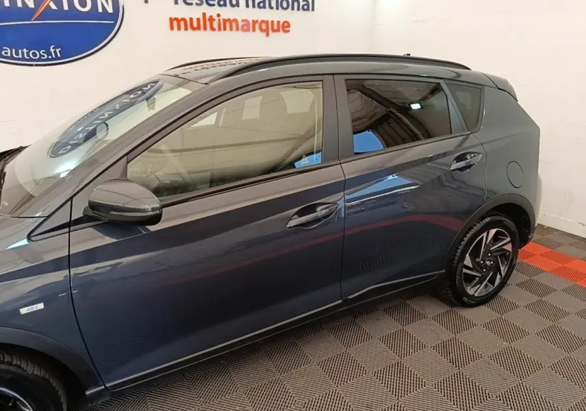 Vue latérale côté gauche d'une Hyundai Bayon gris foncé avec jantes alliage et vitres teintées.