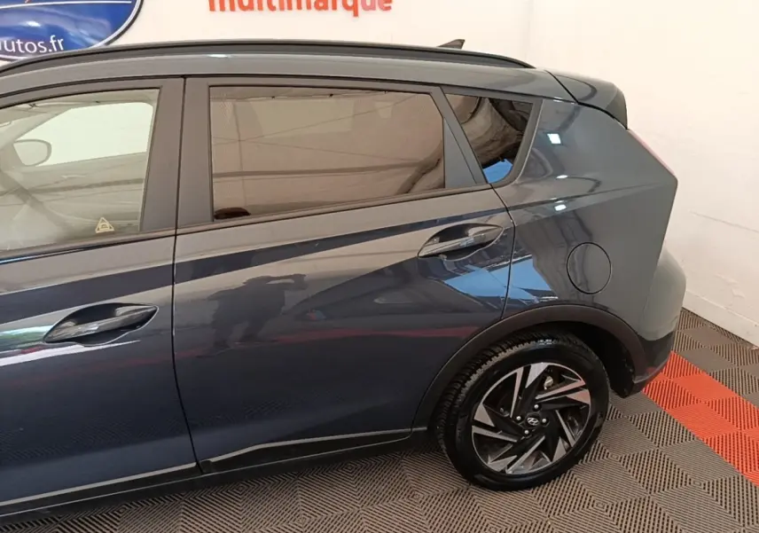 Vue latérale côté droit du Hyundai Bayon gris foncé, mettant en valeur la roue arrière et les lignes du coffre.