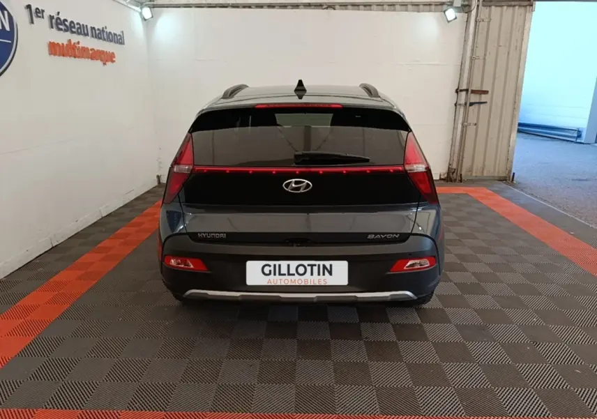 Vue arrière d'une Hyundai Bayon gris foncé 2023 avec feux arrière en bandeau lumineux et logo central visible.