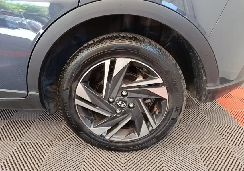 Gros plan sur la roue arrière droite d’une Hyundai Bayon gris foncé avec jante alliage au design géométrique.