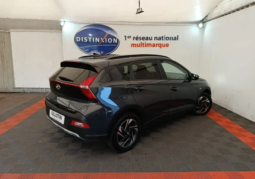 Vue 3/4 arrière droite d'une Hyundai Bayon gris foncé avec feux arrière en forme de boomerang et jantes noires stylisées.