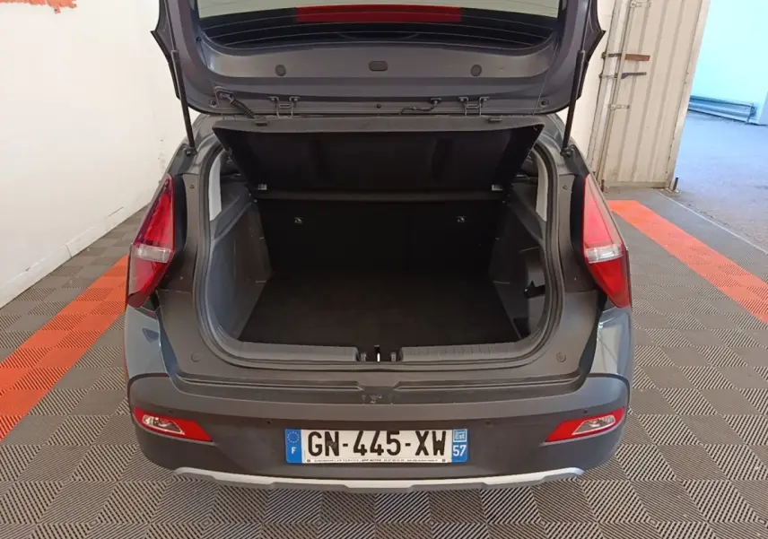 Vue arrière d’un Hyundai Bayon gris foncé avec coffre ouvert montrant l’espace de chargement vide.
