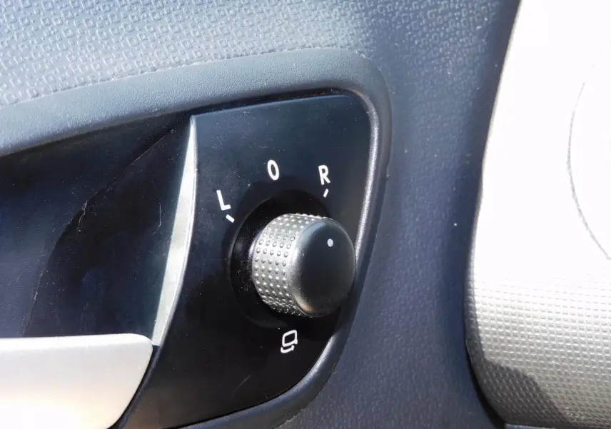 Gros plan sur le bouton de réglage des rétroviseurs côté conducteur de la SEAT Ibiza Cupra noire de 2011.