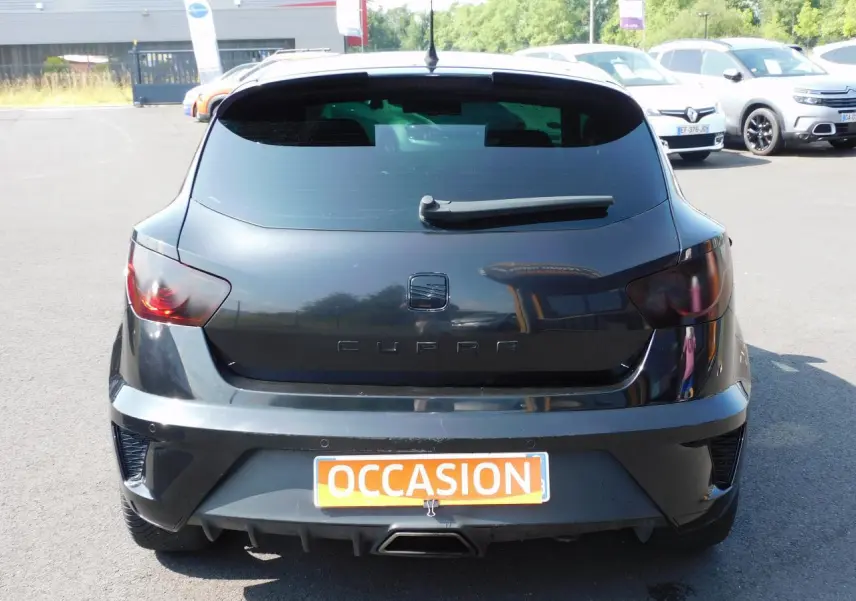 Vue arrière d'une SEAT Ibiza Cupra noire avec sigle CUPRA et sortie d'échappement centrale chromée sur parking.