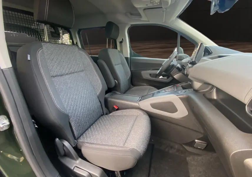 Vue intérieure côté conducteur du Peugeot Rifter 2025 vert Sirkka Green, sièges tissu gris et tableau de bord moderne.