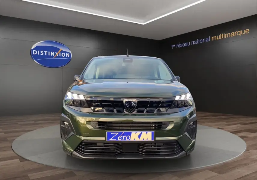 Vue frontale du Peugeot Rifter 2025 en vert Sirkka, avec calandre noire et phares LED allumés.