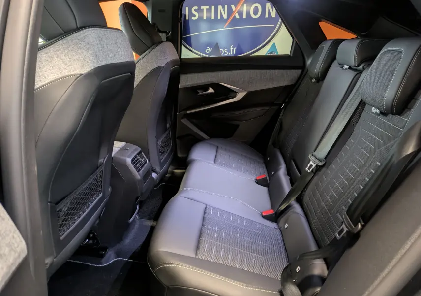 Vue intérieure arrière côté droit du Peugeot 3008 hybride gris titanium, montrant les sièges en tissu et cuir avec ceinture de sécurité.