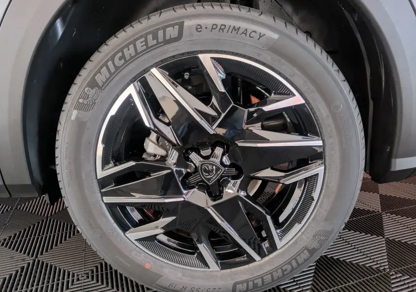 Gros plan sur la roue avant droite du Peugeot 3008 gris titanium, mettant en valeur la jante noire et argentée au design moderne.