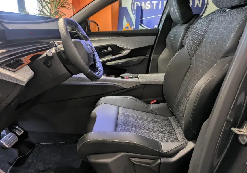 Vue intérieure côté conducteur du Peugeot 3008 gris titanium, mettant en valeur le siège sport et le volant multifonction.