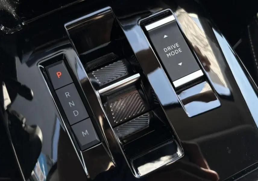 Gros plan sur la console centrale noire brillante du Citroën C4 Hybrid 145 CH avec sélecteur de vitesses et bouton Drive Mode.