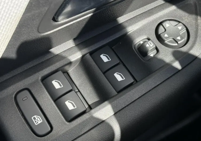Gros plan sur les commandes de lève-vitres et réglages des rétroviseurs côté conducteur d'une Citroën C4 hybride 2025.