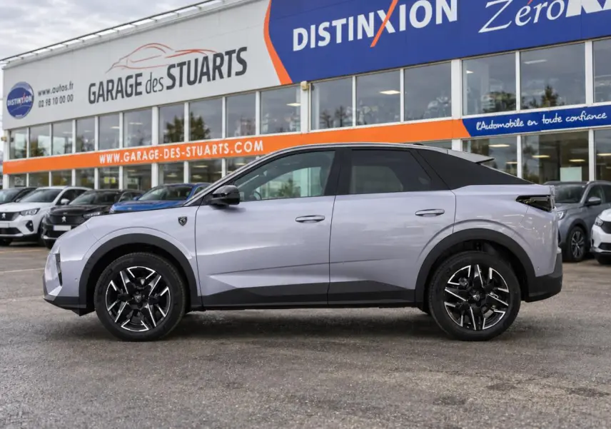 Vue de profil côté gauche du Peugeot 3008 gris Artense avec jantes alliage noires et toit noir, devant un garage.