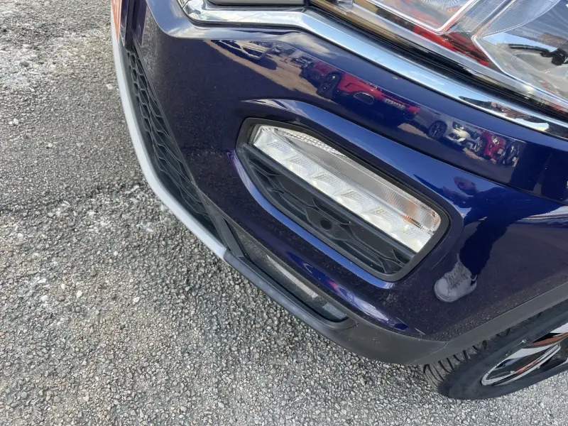 Gros plan sur le feu antibrouillard avant droit du Volkswagen T-Roc gris Urano avec détails du pare-chocs et calandre.