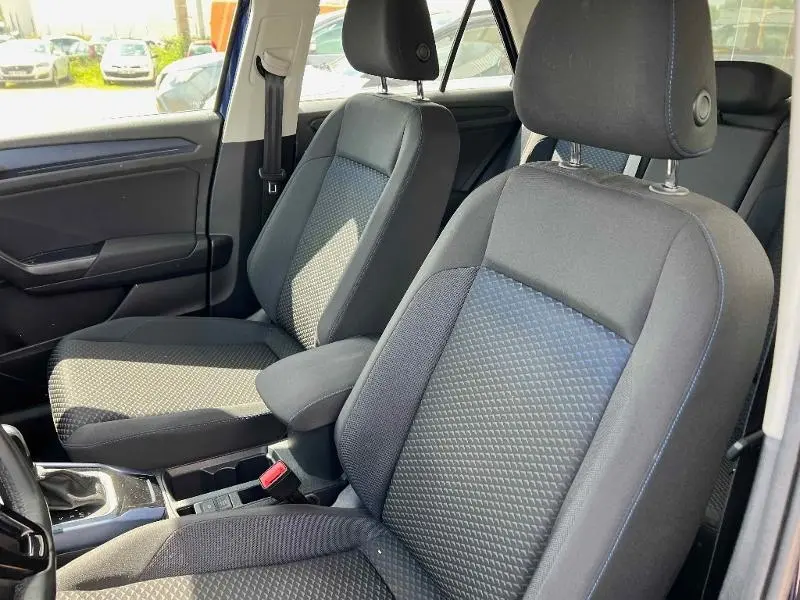 Gros plan sur les sièges avant en tissu gris et noir du Volkswagen T-Roc 1.5 TSI United, avec accoudoir central visible.