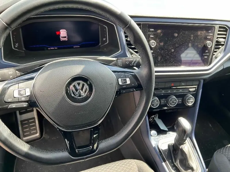 Vue intérieure du volant multifonction et tableau de bord numérique du Volkswagen T-Roc gris 2020 avec console centrale et levier automatique.