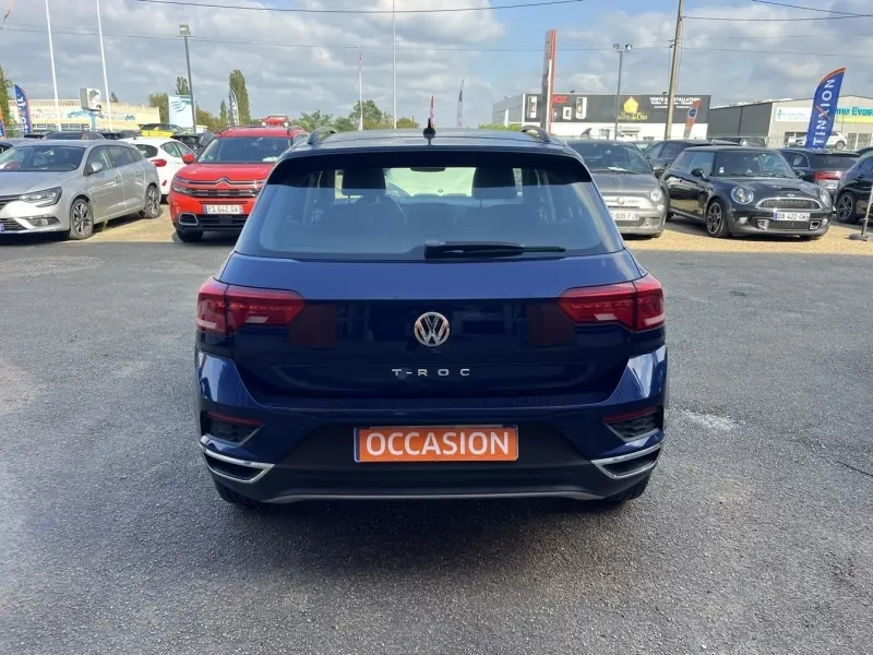 Vue arrière d'un Volkswagen T-Roc gris foncé avec feux LED et plaque orange "OCCASION" sur un parking.