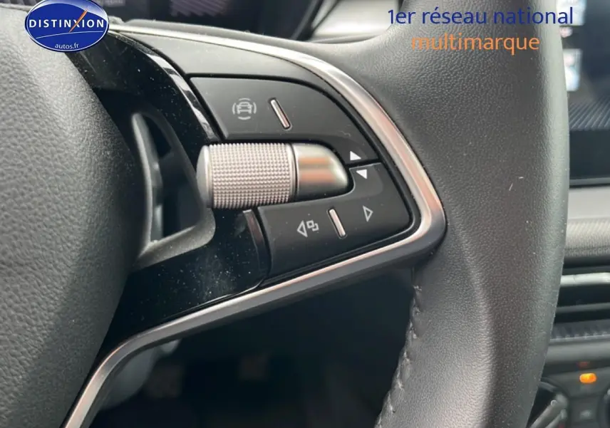 Gros plan sur les commandes gauche du volant cuir multifonction d’une Skoda Fabia blanche 2025.