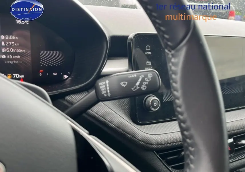 Vue rapprochée du tableau de bord et du volant cuir noir d'une Skoda Fabia blanche, avec écran tactile et commandes au volant.