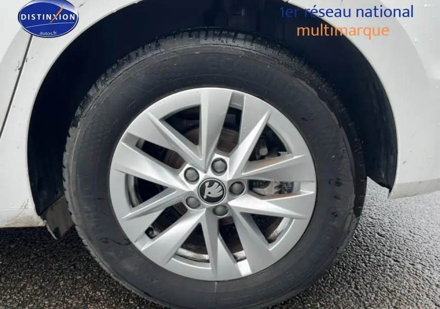 Gros plan sur la roue avant droite blanche d'une Skoda Fabia 2025 avec jante alu et logo central visible.