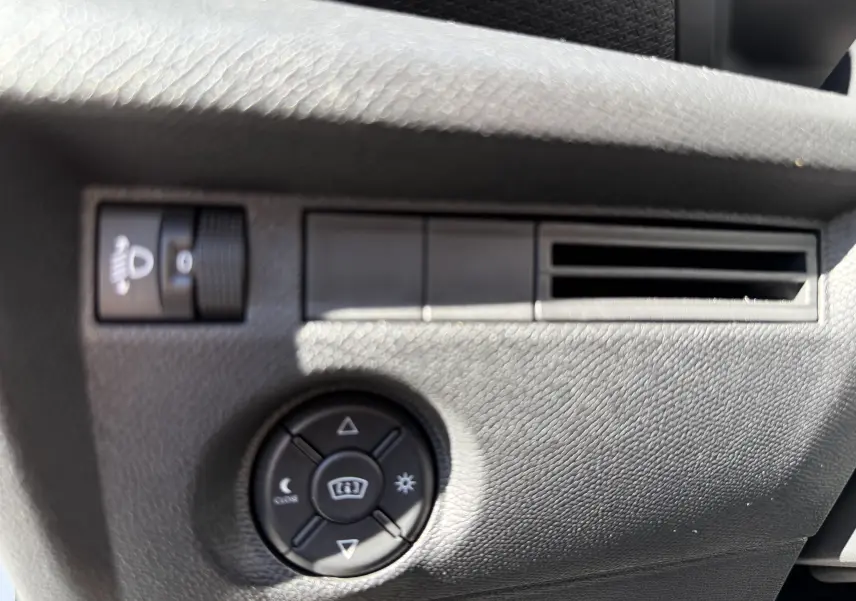 Gros plan sur les commandes d’éclairage et de réglage des rétroviseurs dans l’habitacle noir du Citroën C4 Hybrid 2025.