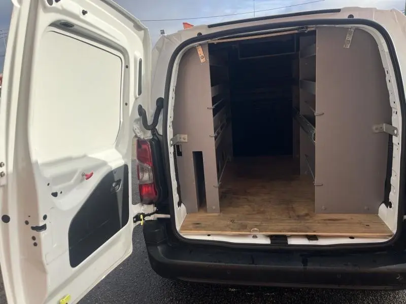 Vue arrière ouverte du Citroën Berlingo Fourgon blanc Banquise montrant l'intérieur aménagé avec étagères et plancher en bois.