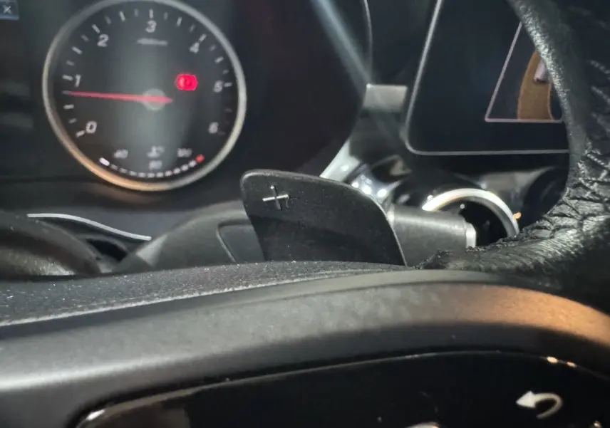 Gros plan sur la palette de changement de vitesse droite et le compte-tours du tableau de bord d'un Mercedes Classe C Break noir 2019.