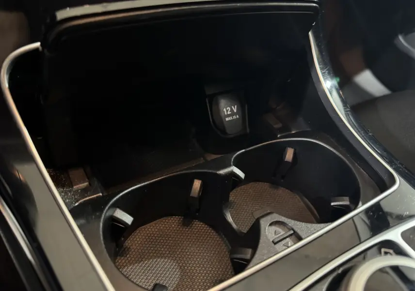 Gros plan sur la console centrale noire du Mercedes Classe C Break C 200 d Business Line avec prise 12V et porte-gobelets.
