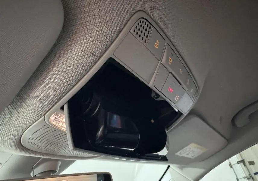 Vue intérieure du plafond d'une Mercedes Classe C Break 2019 noir, avec compartiment lunettes ouvert et commandes éclairage.