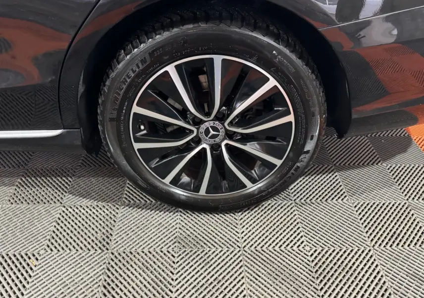 Gros plan sur la roue avant gauche noire d'un Mercedes Classe C Break C 200 d Business Line 2019 avec jante alliage bicolore.