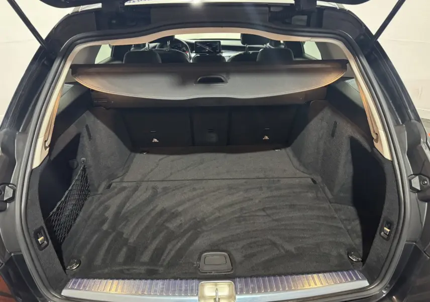 Coffre spacieux noir ouvert d'une Mercedes Classe C Break C 200 d Business Line vue de l'arrière avec cache-bagages déployé.