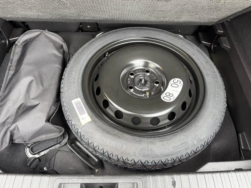 Pneu de secours noir en gros plan dans le coffre d’un Renault Captur 2025, version hybride Rouge Flamme.