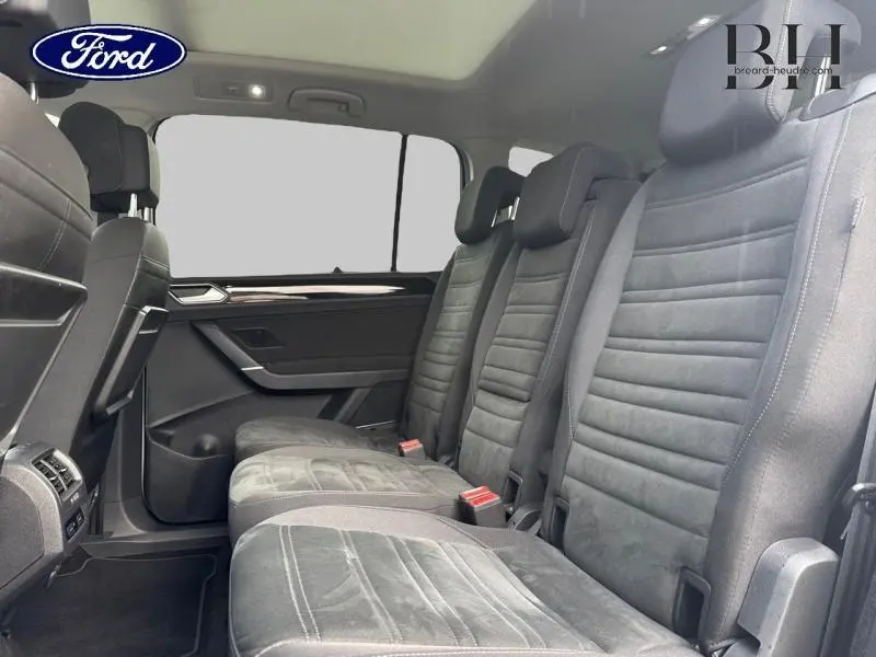 Vue intérieure côté droit sur la deuxième rangée de sièges noirs en tissu du Volkswagen Touran 2021 avec toit ouvrant panoramique.