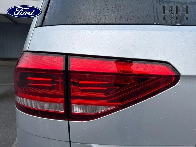 Gros plan sur le feu arrière gauche du Volkswagen Touran 2021 en Reflet d'Argent Métallisée, avec pluie visible.