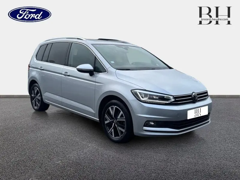 Volkswagen Touran 1.5 TSI Carat 7 places en Reflet d'Argent, vue 3/4 avant avec toit ouvrant panoramique.