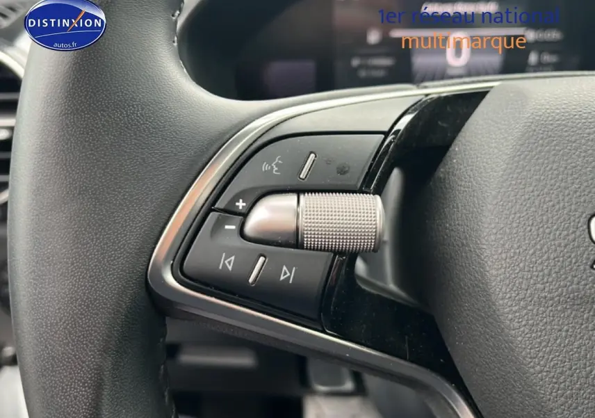Gros plan sur les commandes audio et de volume au volant cuir noir de la Skoda Fabia blanche 2025.