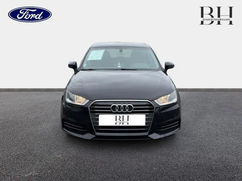 Audi A1 Sportback noir brillant vue de face, mettant en valeur sa calandre hexagonale et ses phares allumés.