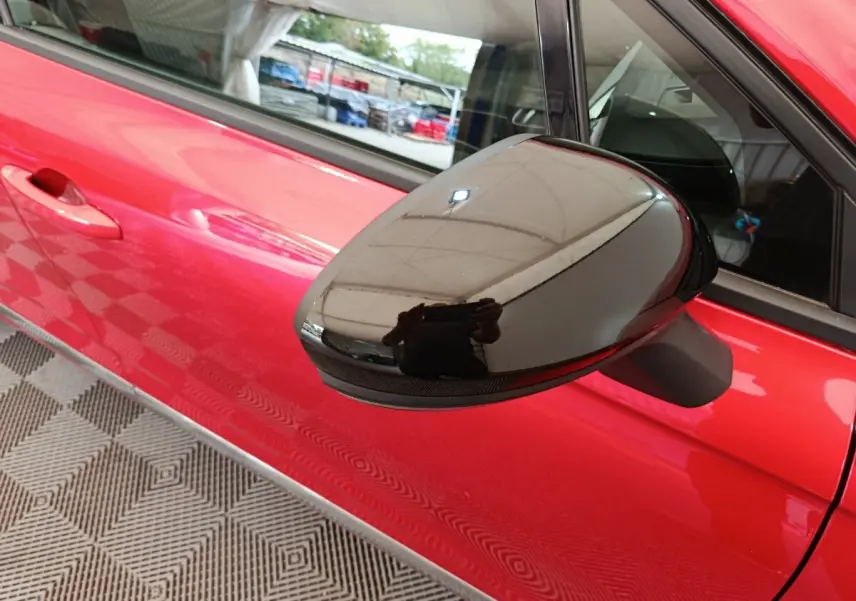 Rétroviseur noir brillant côté gauche sur porte rouge vif d'une Renault Clio Techno TCe 90 -24 vue de profil rapproché.