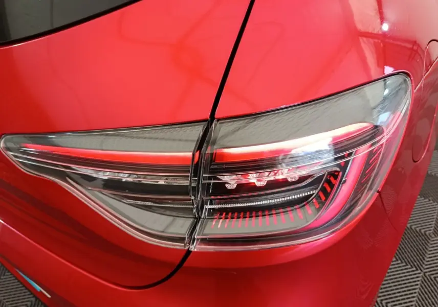 Gros plan sur le feu arrière droit rouge et transparent d'une Renault Clio Techno TCe 90 2024 rouge.