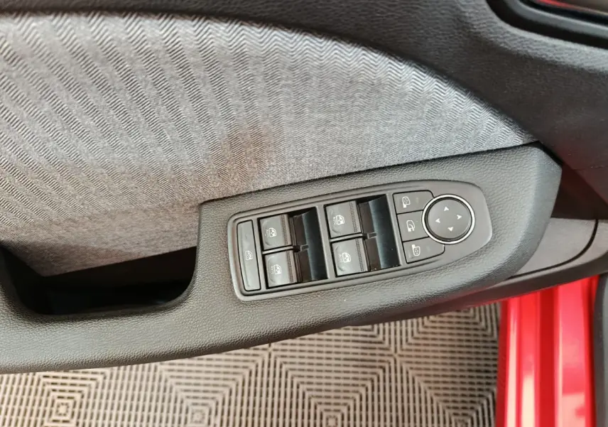Commande des vitres et rétroviseurs sur la porte côté conducteur d'une Renault Clio Techno TCe 90 rouge 2024.